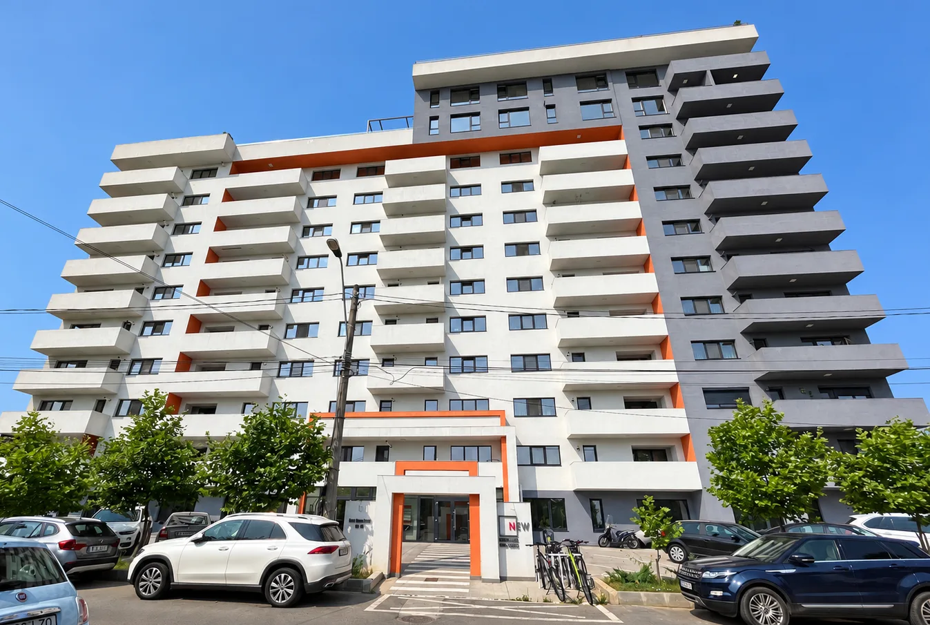 Clădirea Casa Presei văzută din față, cu intrarea principală încadrată în portocaliu și 11 etaje cu balcoane