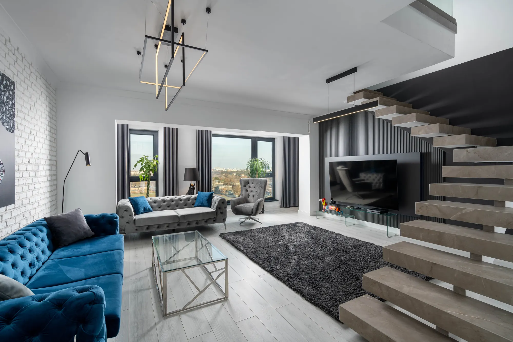 Furnished living room in a Casa Presei duplex penthouse, with a floating staircase